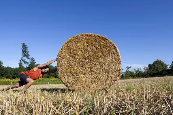 Hombre empujando paca de heno — Foto de Stock