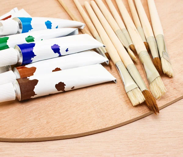 Tubes of colorful paint and paint brush — Stock Photo, Image