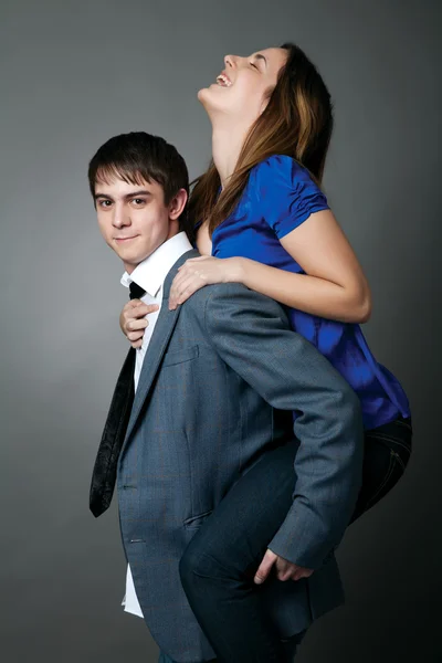 Young couple standing together against a grey wall — Stock Photo, Image