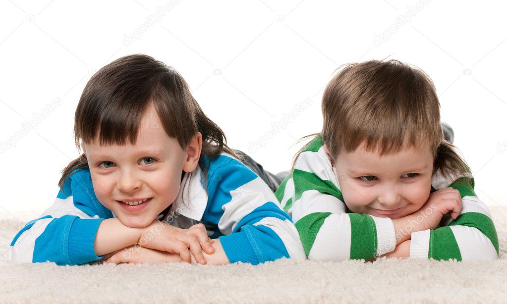 Two boys lie on the carpet
