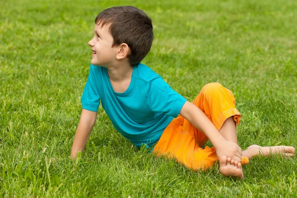 Маленький мальчик на траве смотрит в сторону — стоковое фото
