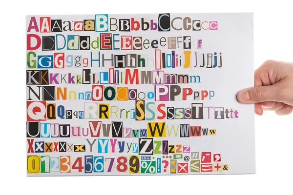 Hand holding newspaper clippings alphabet