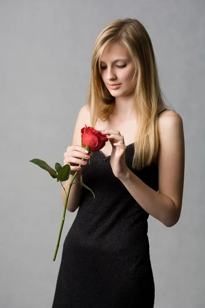 Przepiękny młody blond kobieta przytrzymanie rose. — Zdjęcie stockowe