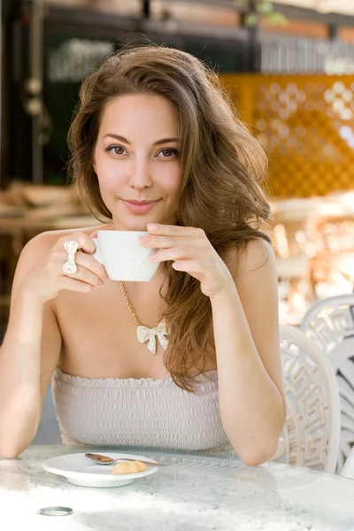 Mooie jonge brunette genieten van koffie. — Stockfoto