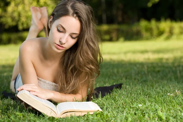 Wunderschöne Brünette liest ein Buch im Park. — Stockfoto