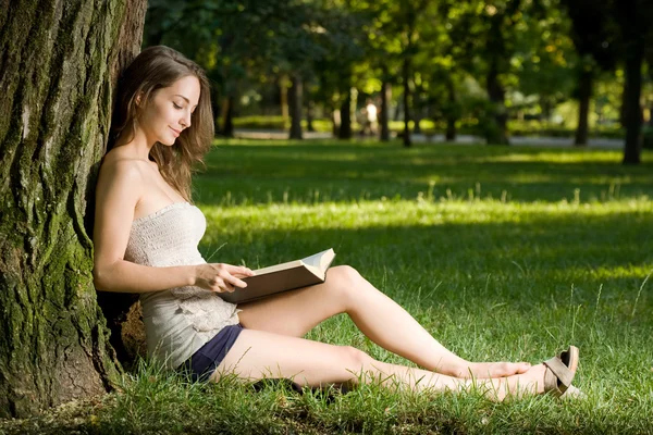 Νεαρή μελαχρινή απολαμβάνει βιβλίο σε εξωτερικούς χώρους. — Φωτογραφία Αρχείου