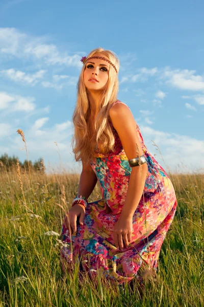 Piękna blond kobieta pozowanie na łące przeciw błękitne niebo — Zdjęcie stockowe
