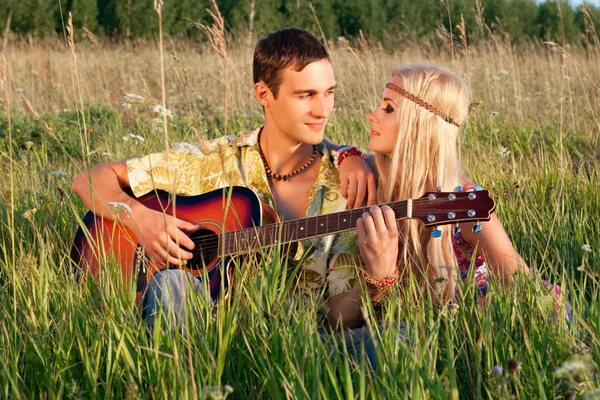 Cute young man and fine woman sit on meadow. young man plays gu — Stock Photo, Image