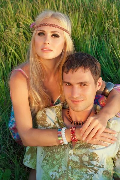 Cute young man and fine woman sit on meadow. — Stock Photo, Image