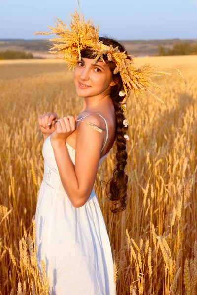 stock image Young woman with chaplet in white dress standing in field