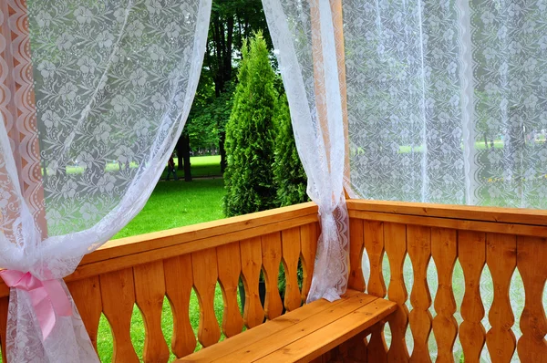 Pórtico de madeira com cortinas de renda e vista jardim — Fotografia de Stock