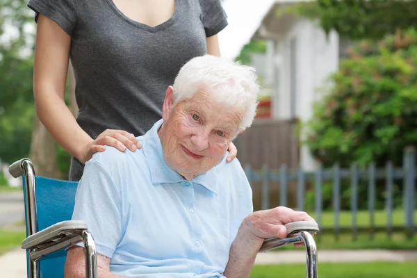 Счастливая пожилая дама в инвалидной коляске с коляской — стоковое фото