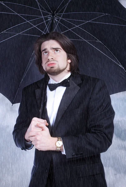 Hombre sosteniendo paraguas bajo la lluvia y el suspiro —  Fotos de Stock