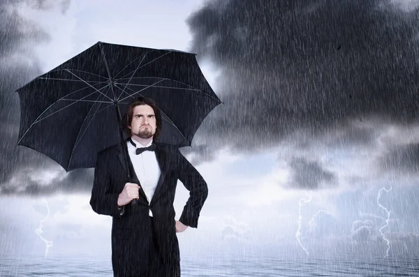 Homme tenant parapluie sous la pluie et fronçant les sourcils — Photo
