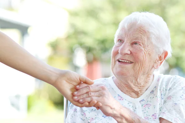 Старшая женщина, держащаяся за руки со смотрителем Лицензионные Стоковые Изображения