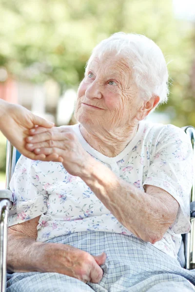 Старшая женщина, держащаяся за руки со смотрителем — стоковое фото