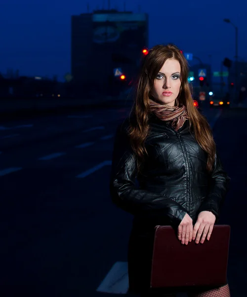Молодая брюнетка бизнес-женщина держит портфель в центре города ночью — стоковое фото