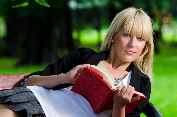 Menina lendo em um banco de parque — Fotografia de Stock