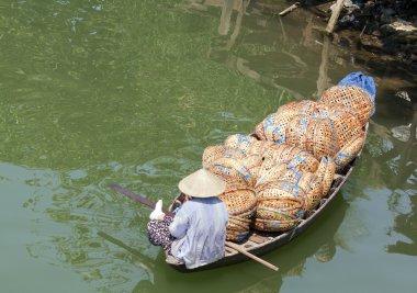 Woman in boat full of baskets, Hoi An, Vietnam clipart