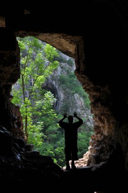 bir mağara girişi önünde duran adam