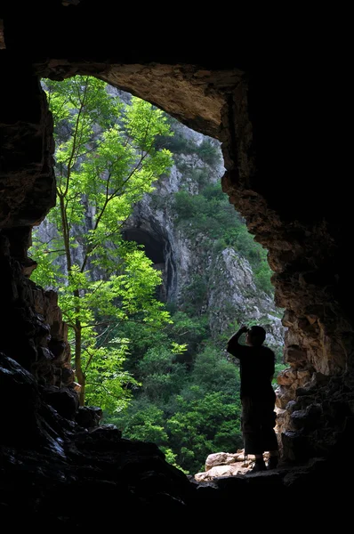 Człowiek stoi przed wejściem do jaskini — Zdjęcie stockowe
