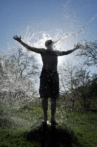 Maschio gode la spruzzata d'acqua in mezzo alla natura — Foto Stock