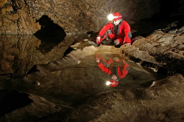 En speleolog reflektion i grottan vatten — Stockfoto