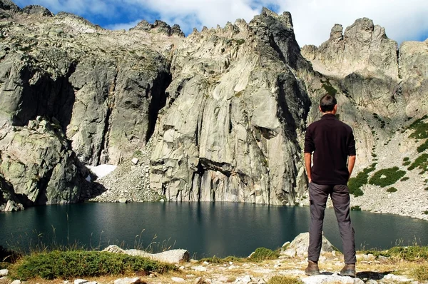 Homem em pé na frente de um lago de montanha — Fotografia de Stock