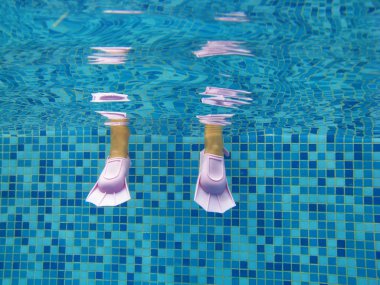 Underwater kid's legs in fins in swimming pool clipart