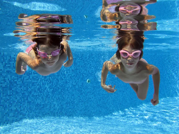 Happy smiling underwater children in swimming pool — Stock Photo, Image