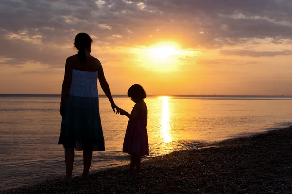 Madre e bambino silhouette sulla spiaggia al tramonto — Foto Stock