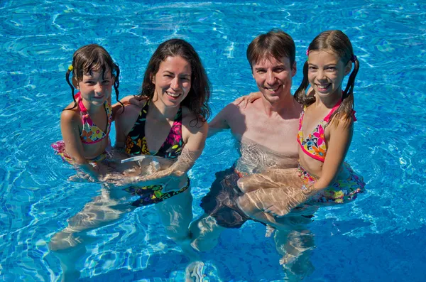 Família feliz com duas crianças na piscina — Fotografia de Stock