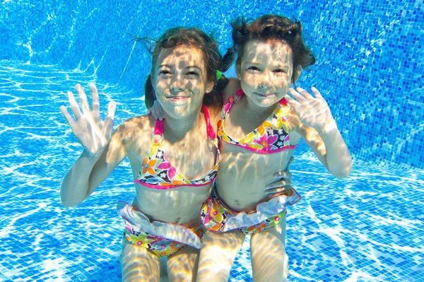 Niños felices sonriendo bajo el agua en la piscina — Foto de Stock