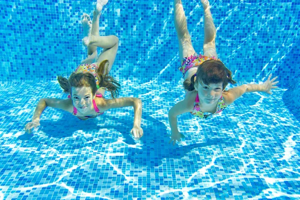 Gelukkige lachende onderwater kinderen in zwembad — Stockfoto