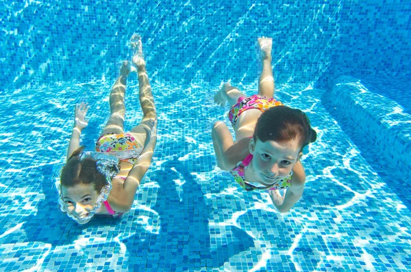 Niños felices sonriendo bajo el agua en la piscina —  Fotos de Stock