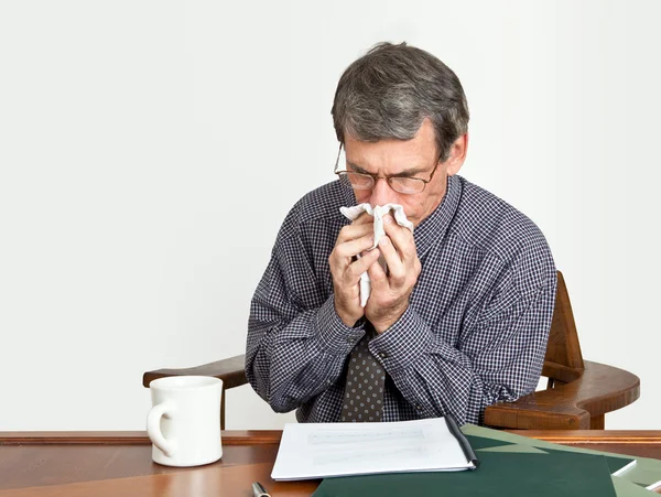 Uomo d'affari alla scrivania soffiare naso — Foto Stock