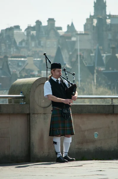 Schotse piper spelen met edinburgh stad achtergrond in kunnen 2012 — Stockfoto