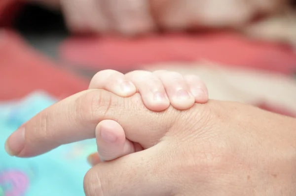 Mother's finger in the hand of child — Stock Photo, Image