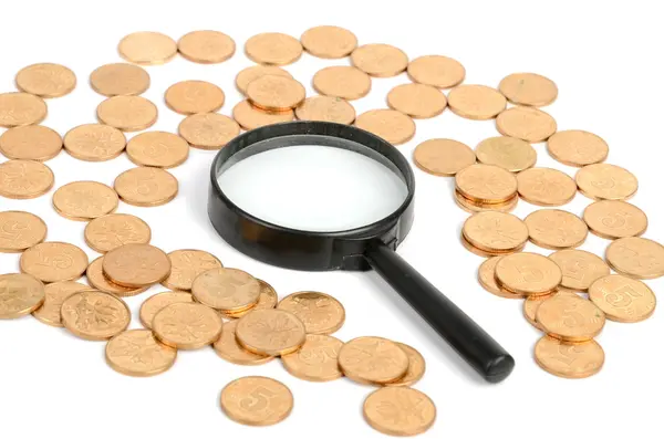 Монеты и лупа — стоковое фото
