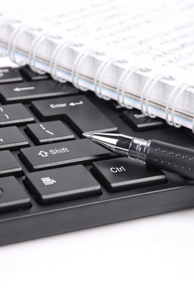 Блокнот і ручка на клавіатурі — стокове фото