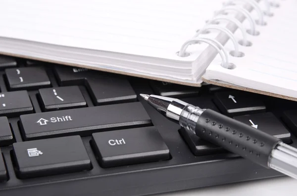 Блокнот и ручка на клавиатуре — стоковое фото