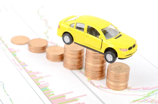 Carro de brinquedo e moedas no gráfico financeiro — Fotografia de Stock
