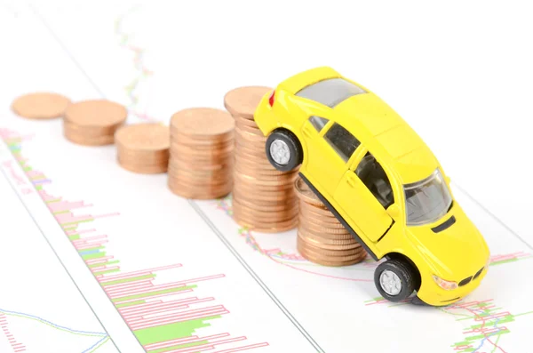 Leksaksbil och mynt på finansiella diagram — Stockfoto