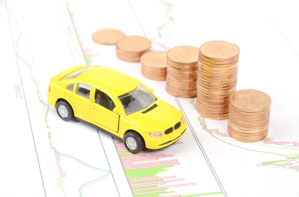 Игрушечный автомобиль и монеты на финансовом графике — стоковое фото