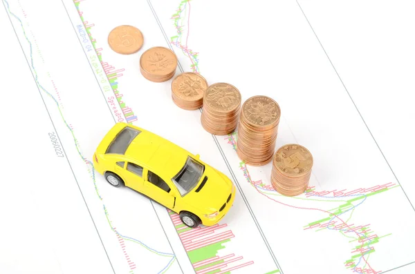 Leksaksbil och mynt på finansiella diagram — Stockfoto
