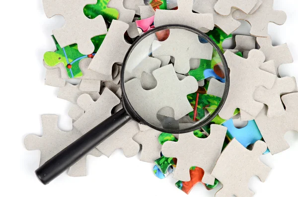 Puzzles and magnifier — Stock Photo, Image
