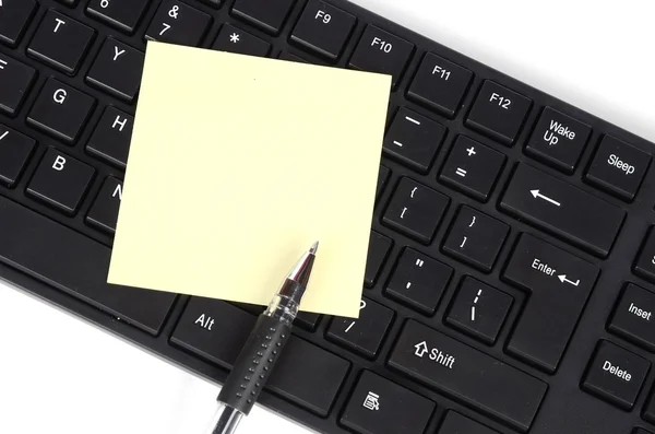 Клавиатура компьютера и блокнот с ручкой — стоковое фото