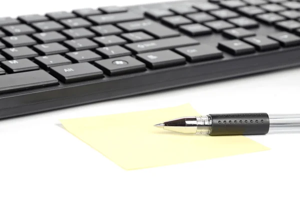 Клавиатура компьютера и блокнот с ручкой — стоковое фото