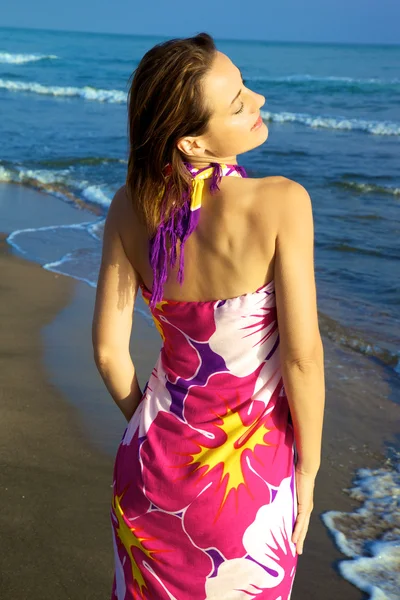 Mooie vrouw die zich voordeed op het strand met kleurrijke jurk — Stockfoto
