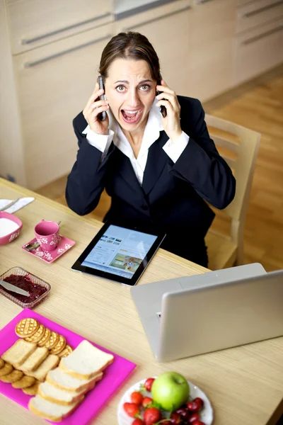 stock image Businesswoman shouting talking with two phones at home